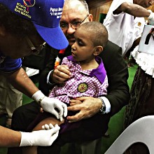 PNG’s PM Peter O'Neil and a child getting vaccinated at today’s polio and measles-rubella launch